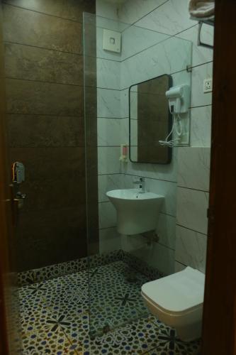 a bathroom with a sink and a toilet and a mirror at Rosewood Grand in Faridabad