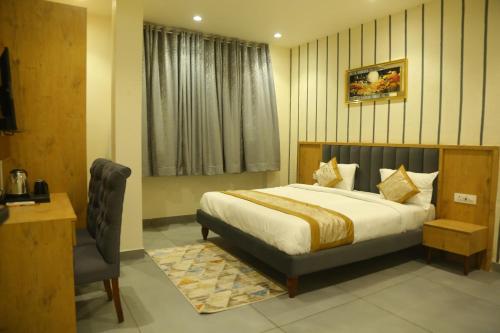 a bedroom with a bed and a desk and a chair at Rosewood Grand in Faridabad
