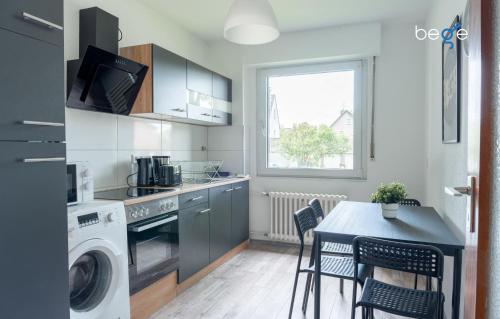 eine Küche mit einer Waschmaschine und einem Tisch mit Stühlen in der Unterkunft BEGE APARTMENTS Corporate Lodge in Gelsenkirchen