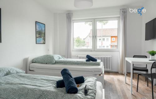 ein Schlafzimmer mit zwei Betten und einem Tisch und einem Fenster in der Unterkunft BEGE APARTMENTS Corporate Lodge in Gelsenkirchen