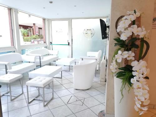 a room with white chairs and tables and flowers at Hotel Nordic in Bellaria-Igea Marina