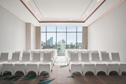 an empty room with white chairs and a large window at voco Ma Belle Danang by IHG in Da Nang