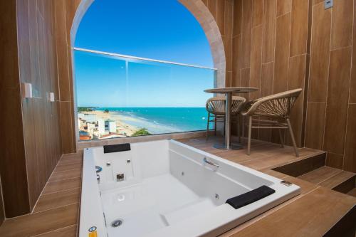 a bath tub in a room with a large window at JANGA HOTEL BOUTIQUE in Maragogi