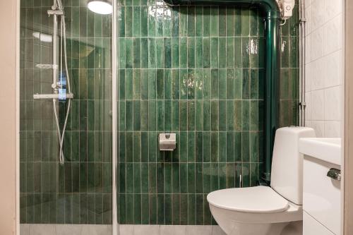 a green tiled bathroom with a toilet and a shower at Merlo Slott in Timrå