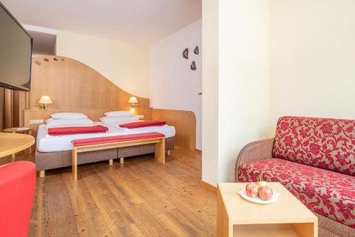 a hotel room with two beds and a couch at Der Kirchheimerhof - Superior in Bad Kleinkirchheim