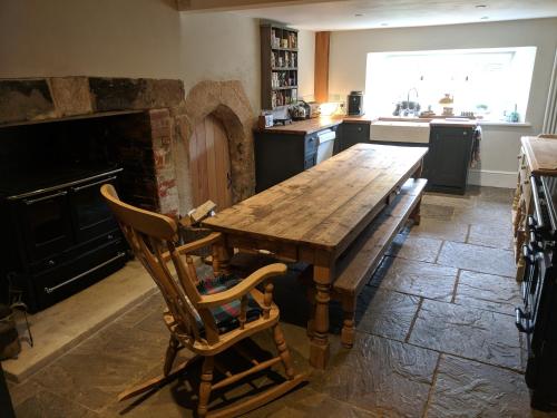 a kitchen with a wooden table and a fireplace at Large Manor House near Bath in Trowbridge