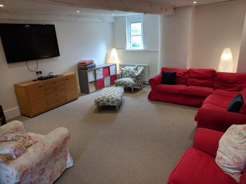 a living room with red furniture and a flat screen tv at Large Manor House near Bath in Trowbridge