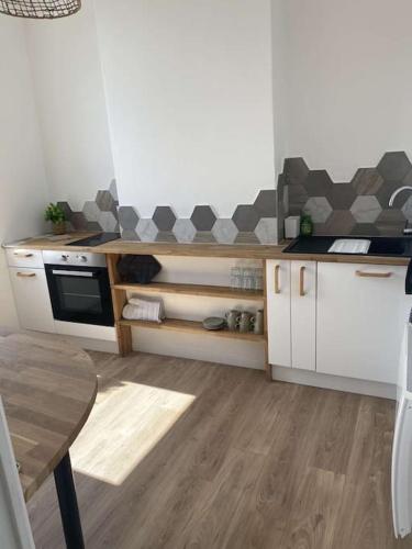 - une cuisine avec des placards blancs, une cuisinière et une table dans l'établissement Appartement vue mer, à Boulogne-sur-Mer
