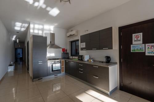 a kitchen with stainless steel appliances and brown cabinets at Spacious Ensuite Bedroom - Gzira in Il-Gżira