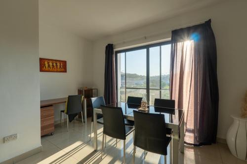 a dining room with a table and chairs and a large window at Spacious Ensuite Bedroom - Gzira in Il-Gżira