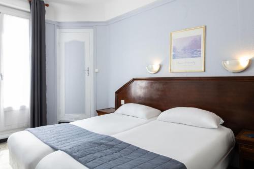 a bedroom with a large bed with a wooden headboard at Hôtel Ambassadeur in Paris