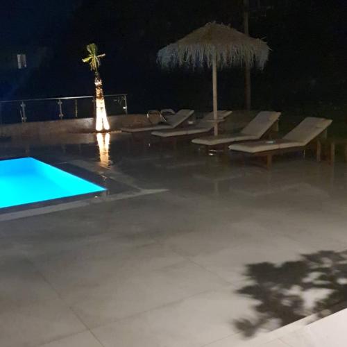 a pool with lounge chairs and an umbrella at night at Villa petros in Malia