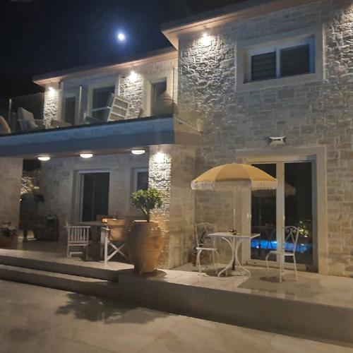 a house at night with a table and an umbrella at Villa petros in Malia