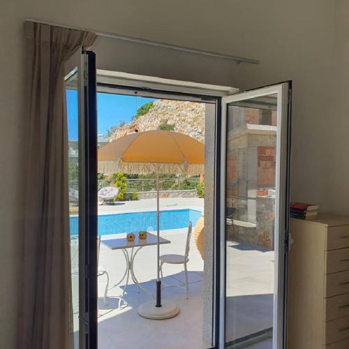 a glass door leading to a patio with a table and an umbrella at Villa petros in Malia