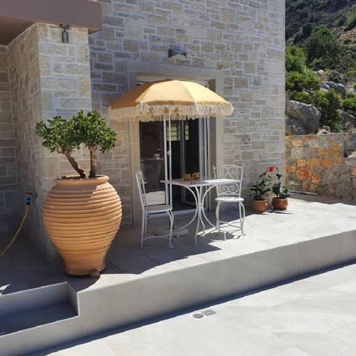 a patio with a table and an umbrella and a vase at Villa petros in Malia