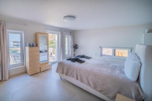 a bedroom with a bed with a dresser and windows at Villa petros in Malia