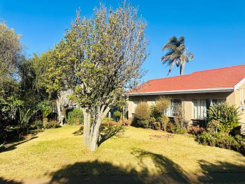 a house with a tree in front of a yard at Horizon Bed and Breakfast in Roodepoort