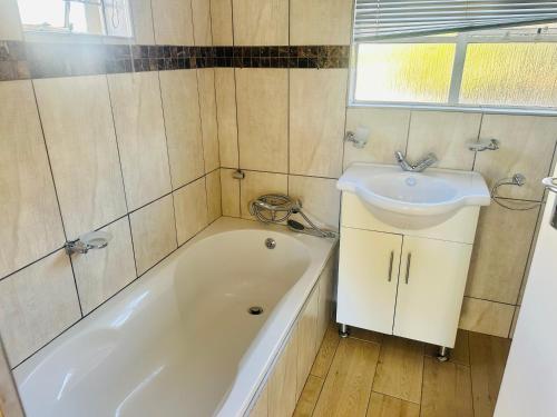 a bathroom with a white tub and a sink at Horizon Bed and Breakfast in Roodepoort
