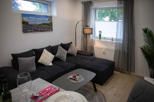 a living room with a black couch and a table at HANNIBAL - Design Apartment Lavendel 4, VW Nähe, Parkplatz, Küche, HighSpeed-WLAN, Fitness, Solarium in Wolfsburg