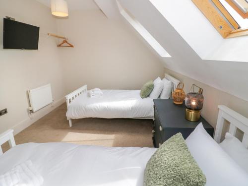 a attic bedroom with two beds and a tv at Little Acre in Evesham