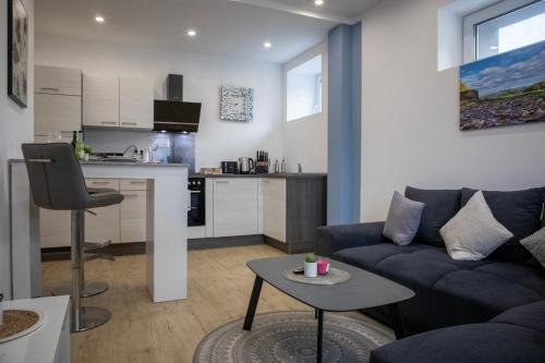a living room with a blue couch and a kitchen at HANNIBAL - Design Apartment Lavendel 4, VW Nähe, Parkplatz, Küche, HighSpeed-WLAN, Fitness, Solarium in Wolfsburg