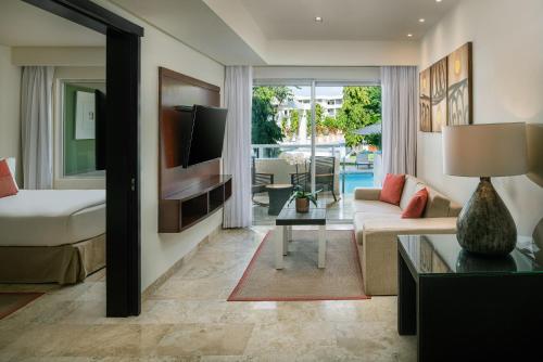 a living room with a bed and a couch and a tv at Paradisus Playa del Carmen - Riviera Maya - All Inclusive in Playa del Carmen