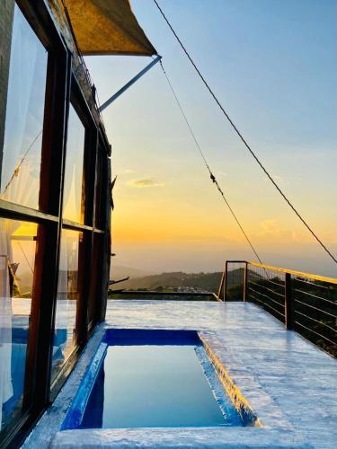 a swimming pool on top of a building with the sunset at Tradición Lodge in Manizales
