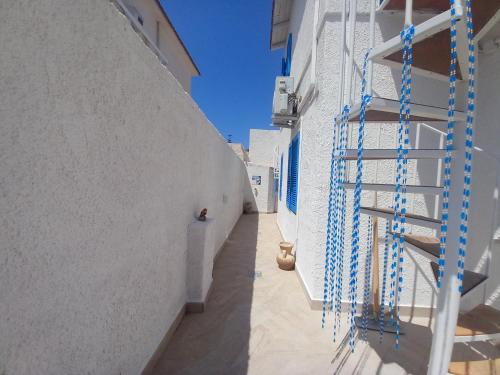 a hallway of a white building with blue racks at TOLUAMMARE Sicily in Santa Maria Del Focallo
