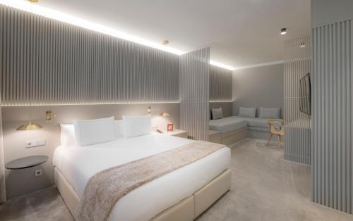 a bedroom with a large white bed and a couch at Carlemany Girona in Girona