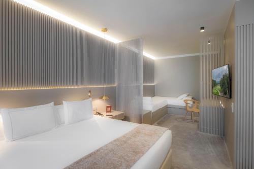 a bedroom with a large white bed and a desk at Carlemany Girona in Girona