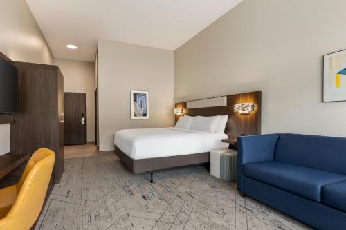 a hotel room with a bed and a blue couch at Holiday Inn Express & Suites Rhinelander by IHG in Rhinelander