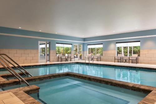 a pool in a hotel with tables and chairs at Holiday Inn Express & Suites Rhinelander by IHG in Rhinelander