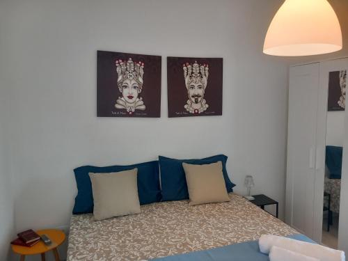 a bedroom with a bed with three pictures on the wall at TOLUAMMARE Sicily in Santa Maria Del Focallo
