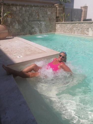 a woman is laying in a swimming pool at Vianova Affittacamere in Giurdignano