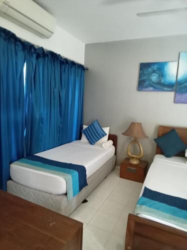 two beds in a room with blue curtains at Mount Marina Villas 12 in Galle