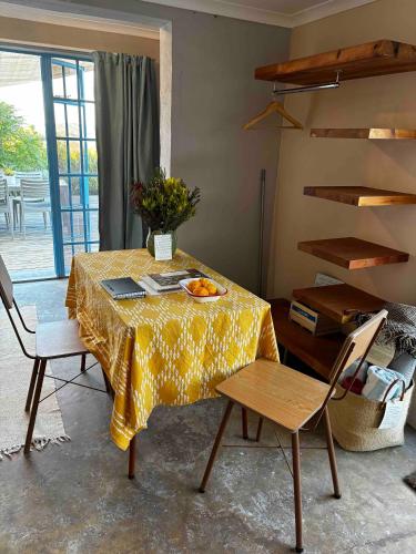 a dining room table with a yellow table cloth and chairs at Starry Starry Night - Route 62 in Montagu