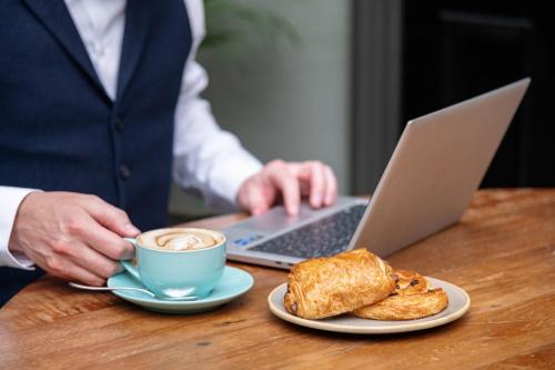 a person sitting at a table with a cup of coffee and a laptop at Kimpton Charlotte Square by IHG in Edinburgh