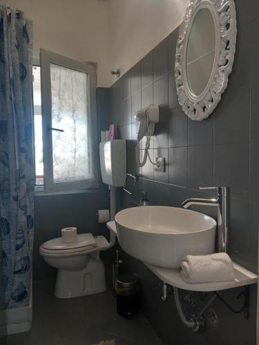 a bathroom with a sink and a toilet and a mirror at TOLUAMMARE Sicily in Santa Maria Del Focallo