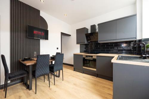 a kitchen with a table and chairs and a kitchen with a counter at Stylish 2BR Home Sleeps 6 Cinema Room, Fast WiFi, Ideal for Short & Long Stays in Leigh