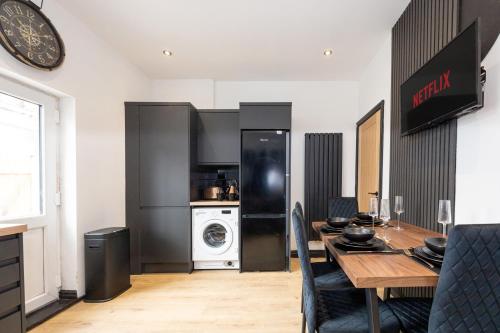 a dining room with a table and a kitchen at Stylish 2BR Home Sleeps 6 Cinema Room, Fast WiFi, Ideal for Short & Long Stays in Leigh