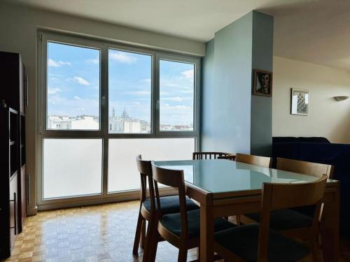 une salle à manger avec une table et des chaises et une grande fenêtre dans l'établissement FLAT with TOUR EIFFEL view and Montmartre, à Paris