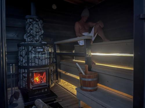 a man sitting on the ledge of a wood stove at traumHaff Lotsen Romantik-Ostsee mit Kamin, privates NORDICSPA und Boot in Rieth