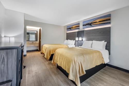 a hotel room with two beds and a television at Quality Inn Glasgow in Glasgow