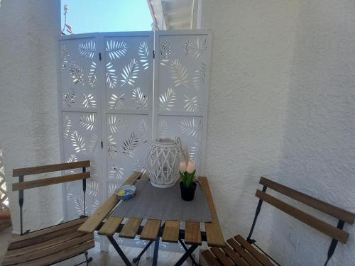 a table and two benches in front of a wall at TOLUAMMARE Sicily in Santa Maria Del Focallo