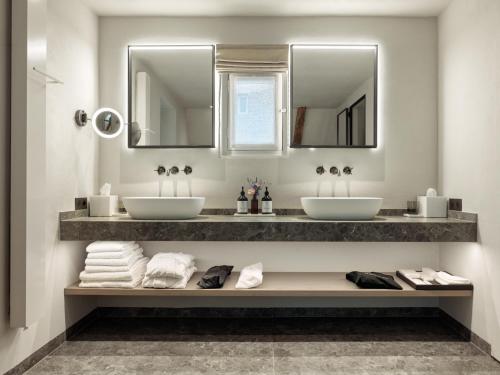 two sinks in a bathroom with mirrors and towels at Botanic Sanctuary Antwerp - The Leading Hotels of the World in Antwerp