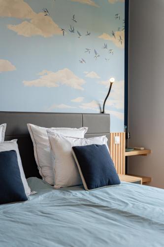 a bed with blue and white pillows and a painting at Manoir du Moulin in Berloz
