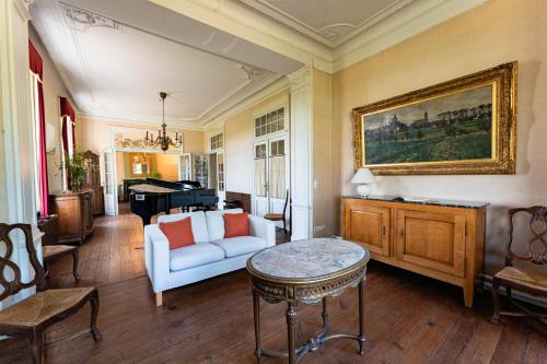 a living room with a white couch and a piano at Manoir du Moulin in Berloz
