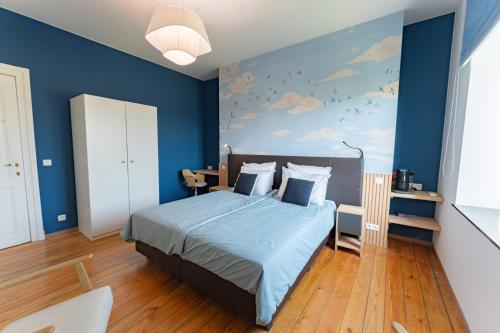 - une chambre bleue avec un lit et un mur bleu dans l'établissement Manoir du Moulin, à Berloz