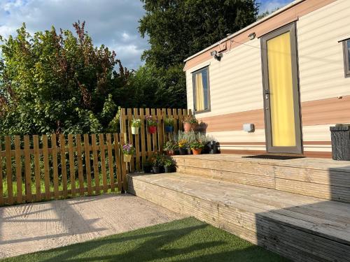 a wooden fence next to a house with flowers at Hare Meadow Lodge in Mellor