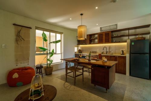a kitchen with a wooden table and a refrigerator at Camfusion House in Hoi An